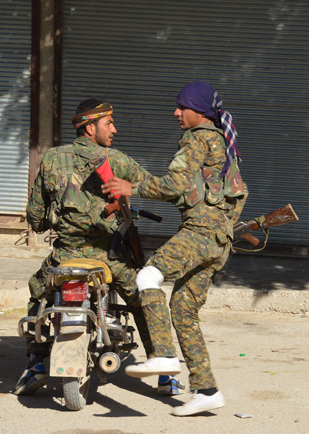 Kobane sokaklarında biri dizinden yaralı iki YPG savaşçısı