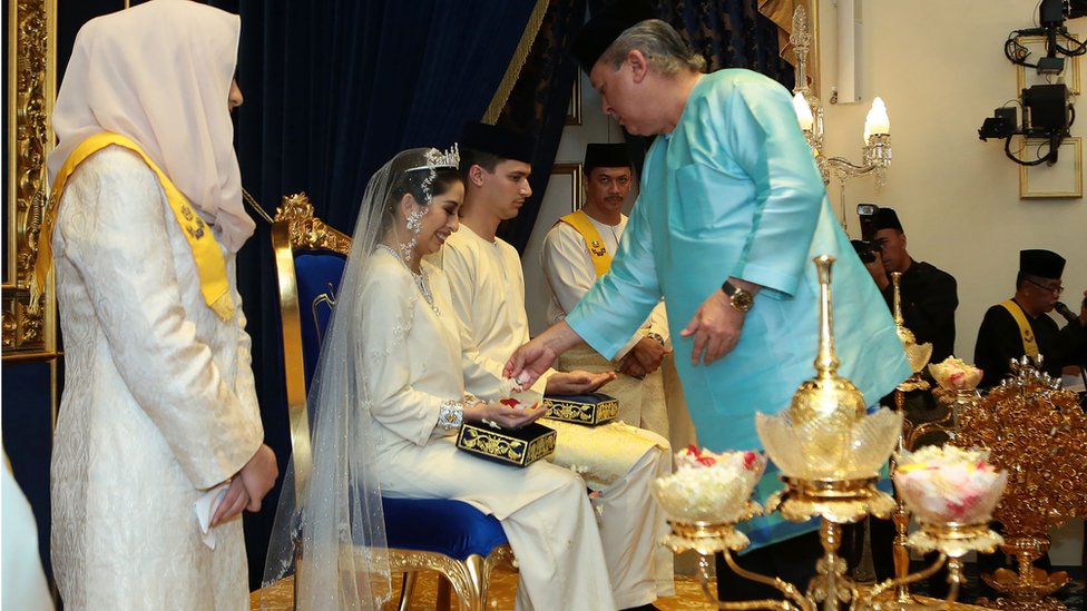 
                    Prenses Tunku Tun İskenderiye, Johor Sultanı İbrahim İsmail'in altı çocuğundan biri ve tek kızı. Törende genç prenses, Malezya geleneklerine uygun şekilde babasının onayını ve duasını aldı. Yeni evli çifte daha sonra okunmuş su ve sarı pirinç serpildi.
                