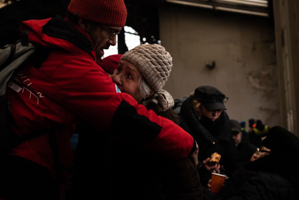 Lviv tren istasyonunda bir adam, ayrılacağı yaşlı annesine sarılıyor.