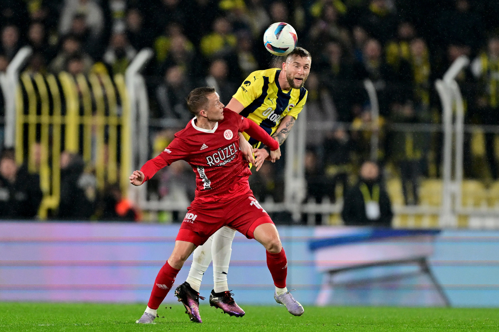 Cem Dizdar: Neredeyse her hafta dilekçeyi kapanın birilerini şikayet için soluğu Adliye’de aldığı ‘’süper münakaşa ligi’’nde puanı değilse de moral üstünlüğü alan Fenerbahçe, yelkenini de rüzgarla doldurmuş görünüyor. ‘’Yerli hakem’’ Cihan Aydın’ın yönettiği maçta Galatasaray - gerçi karşılıklı iki penaltı da ‘’yabancı VAR’’dan verildi ya - Kasımpaşa’ya takılınca Kadıköy’deki maçın sonucundan daha önemlisi heyecan ve eğlence katsayının ne olacağıydı. İlk devre topla oynama oranları eşit olsa da pozisyon, yaratıcılık gibi futbola dair her başlıkta önde olan Fenerbahçe maçı o bölümde bitirdi. Dolayısıyla ikinci devre tempo düştüyse de durum değişmedi. Antalya ilk devre gibi ama Fenerbahçe ilk devre temposunun da yaratıcılığının da gerisinde sürdürdü 70’lere kadar maçı.... (Fanatik)