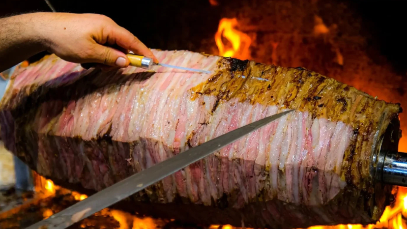 9. Cağ Kebabı, Türkiye: Cağ kebabı, kuzu etinin ön kol kısmından hazırlanan, şişe geçirilerek ateşte pişirilen bir kebap çeşididir. Etler, özel baharatlar ile marine edildikten sonra, şişe geçirilerek odun ateşinde yavaş yavaş pişirilir. Bu pişirme yöntemi, etin yumuşak ve lezzetli olmasını sağlar.
