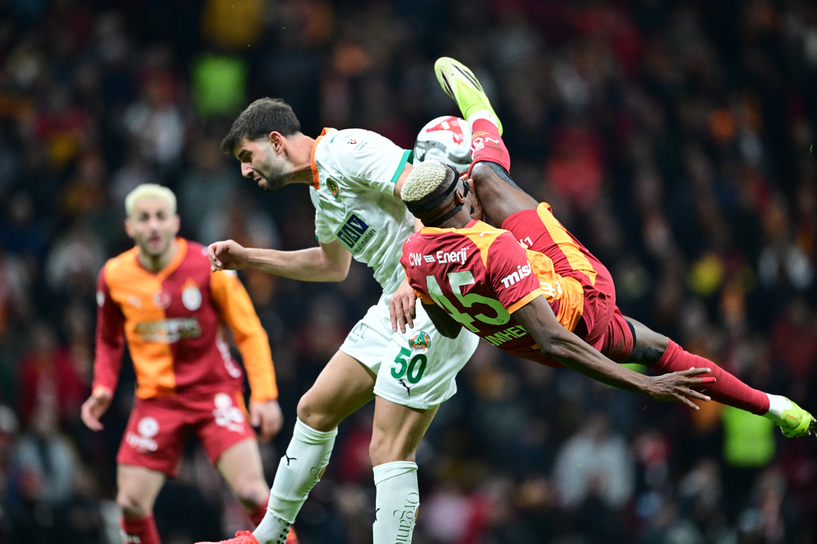 Engin Verel: İlk yarının uzatma dakikalarında Boey'nin golü de maçın bir başka unutulmaz anlarındandı. Boey, asıl işi gol atmak olmamasına rağmen bu işin aslında çok da zor olmadığını kanıtladı. Doğru yere, doğru vuruşu yaparak Galatasaray'ın soyunma odasına galip gitmesini sağladı. İkinci yarıda Alanya cesur oyununun karşılığını erken aldı. Harika bir golle eşitliği sağladı. Ama Galatasaray'da baştan da söylediğim gibi çok fazla özel yeteneğe sahip oyuncu var. En zor anlarda biri sahneye çıkıp işleri düzeltebiliyor. Osimhen'in röveşataya kalkıp da vuramadığı pozisyonda Torreira'nın sezgileri, çabukluğu ve iş bitiriciliği yeniden Galatasaray'a 3 puanın yolunu açtı. Osimhen'in adını soyisim olarak taşıyan Alanya kalecisinin hatasından sonra ise konuk takımın puan umutları bitti. Avrupa'dan yorgun dönen Galatasaray, zor maçlar serisine 3 puanla başlayıp moral tazeledi. (Akşam)